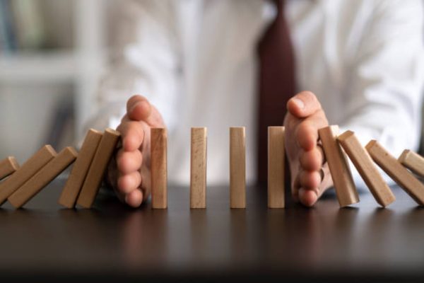 Businessman Stop Domino Effect. Risk Management and Insurance Concept